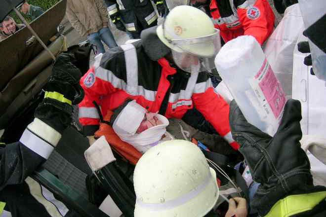 Helfer des Roten Kreuzes versorgen Zusammen mit der Feuerwehr einen Schwerverletzten, der in einem PKW eingeklemmt ist. Das Bild entstand während einer Übung.