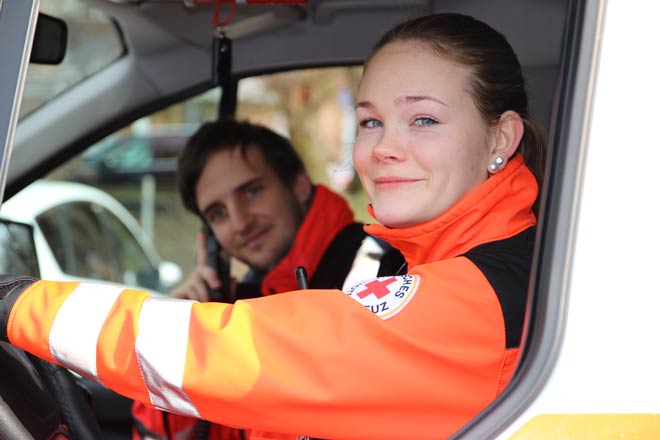 Foto zeigt junge Frau und jungen Mann in Rettungsdienstbekleidung in Rettungswagen