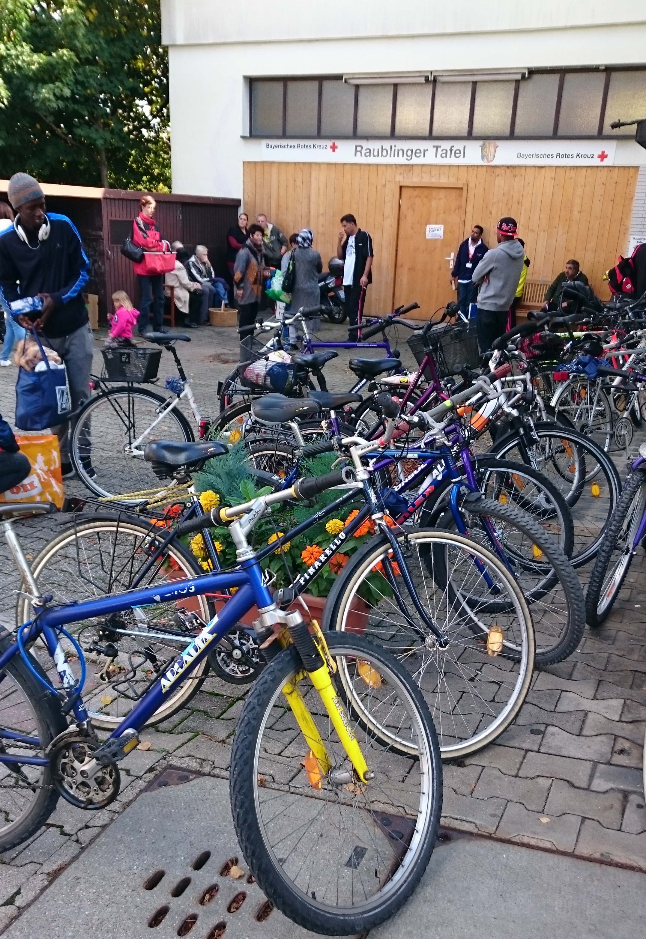 Foto zeigt  Menschen und ihre Fahrräder vor der Tafel in Raubling